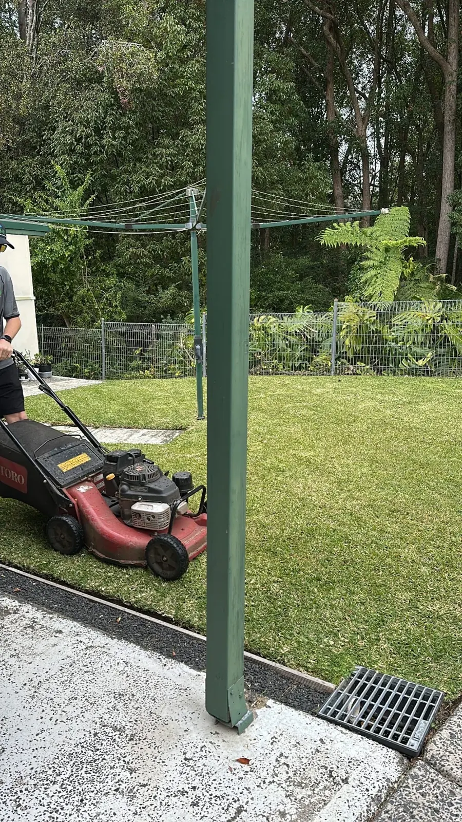 Lawn mowing beside a backyard clothesline