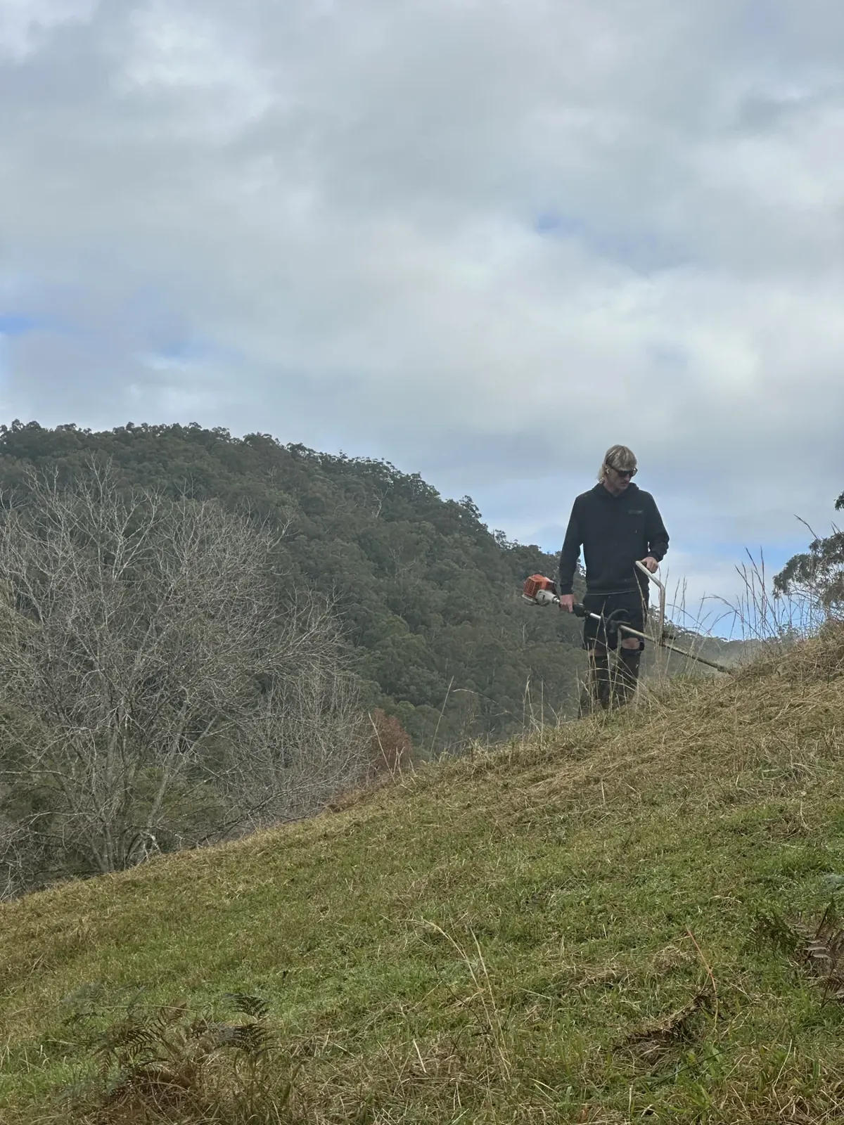 Operating a brushcutter on a grassy slope